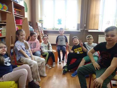 Grupa uczniów siedząca w kole, w tle przestrzeń klasowa.