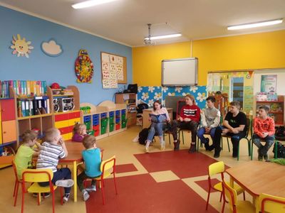 Zdjęcie przedstawia uczniów klasy VII oraz przedszkolaków podczas spotkania czytelniczego.