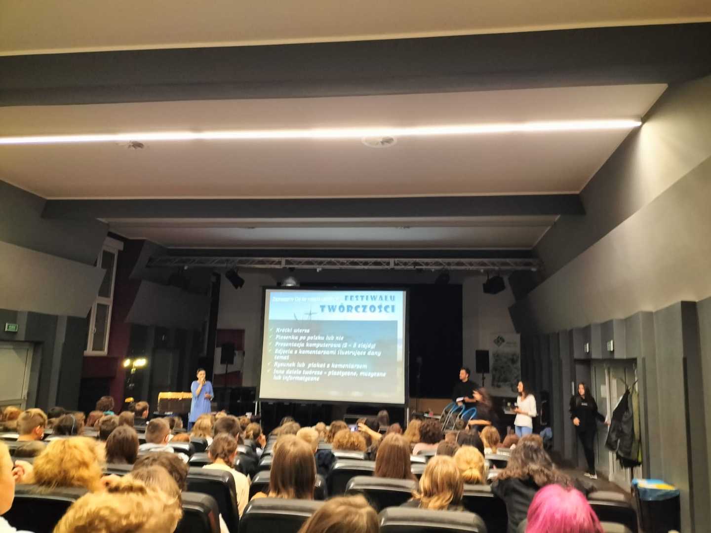 Uczniowie w sali kinowej oglądają prezentację.