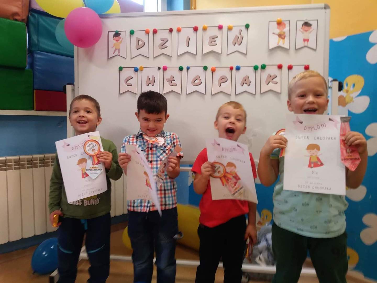Zdjęcie przedstawia uśmiechniętych przedszkolaków w pelerynach Superbohaterów.