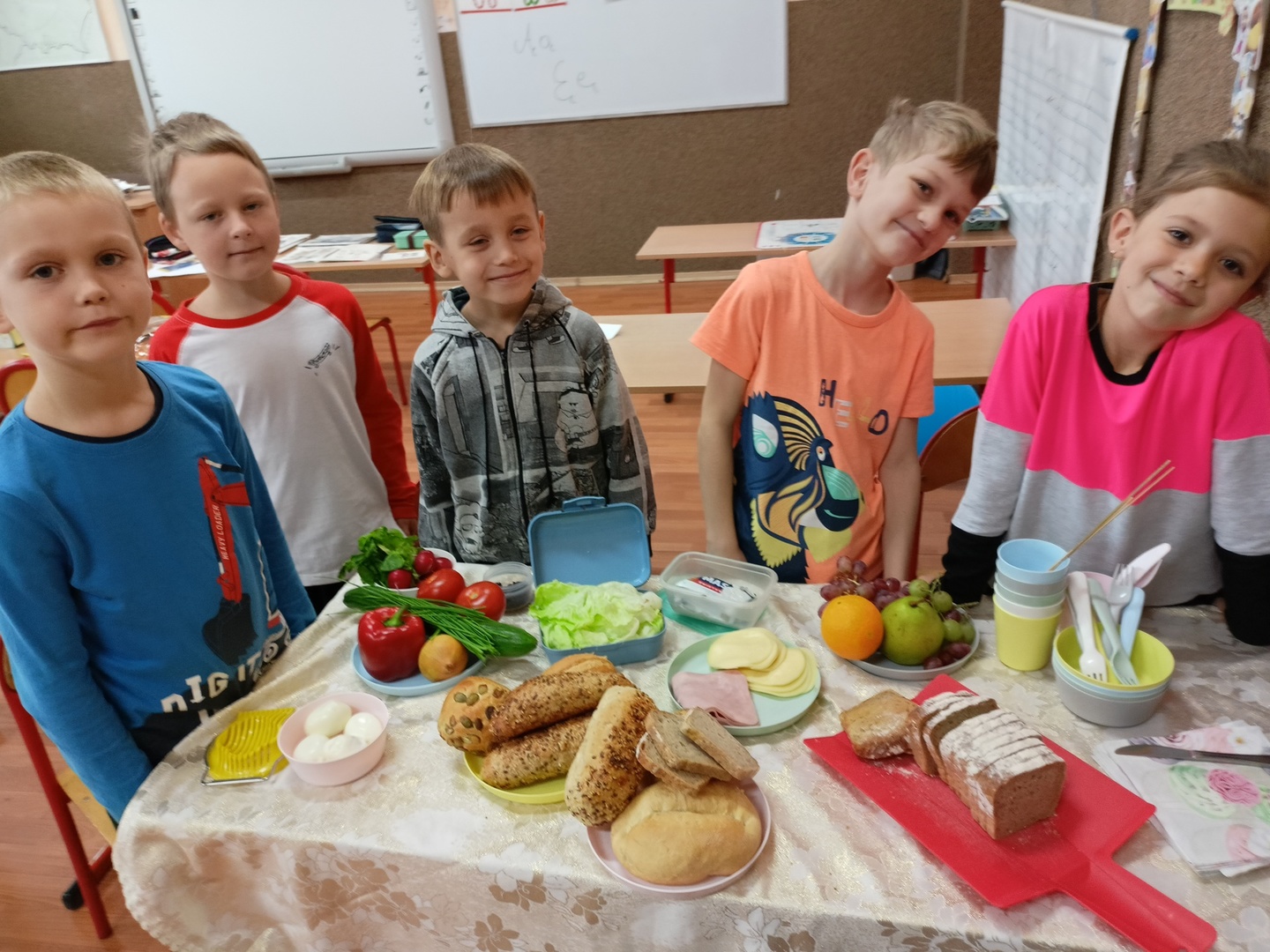 Uczniowie wokół z stołu z artykułami spożywczymi potrzebnymi do przyrządzenia zdrowych kanapek.