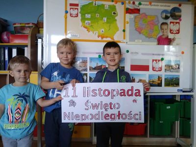 Na zdjęciu przedszkolacy, w tle sala przedszkolna oraz napis „11 listopada Dzień Niepodległości”.