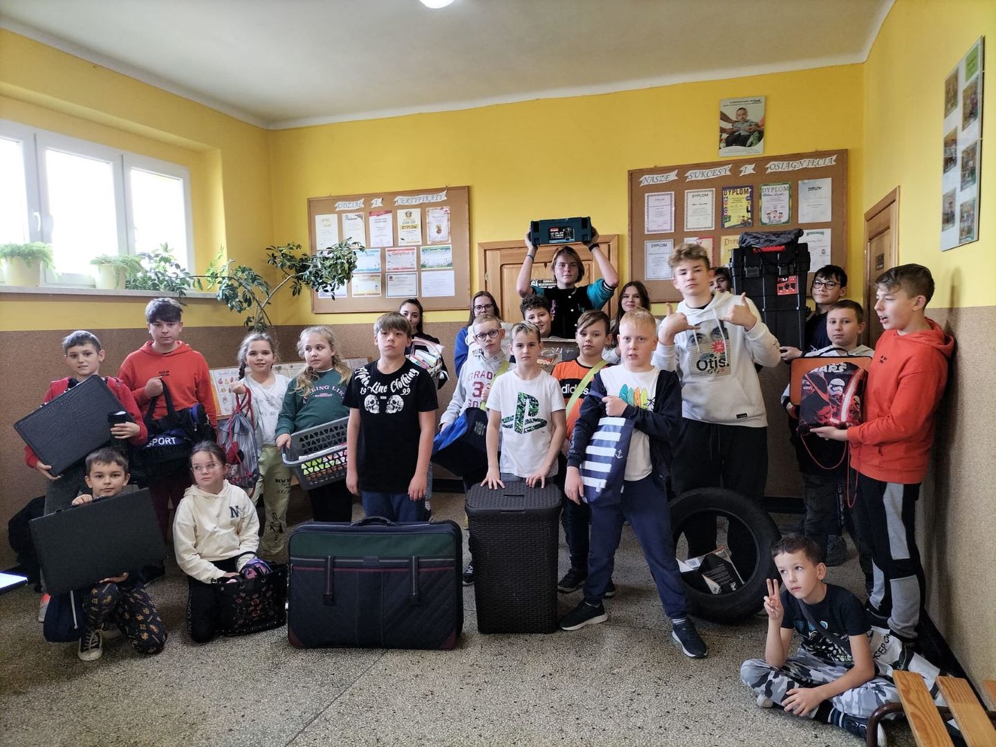 Uczniowie na szkolnym korytarzu z wybraną przez siebie formą plecaka.