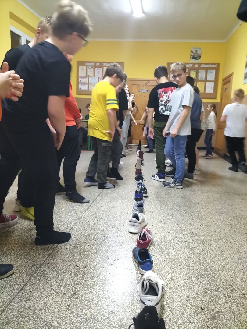 Uczniowie w trakcie wróżb andrzejkowych na szkolnym korytarzu.