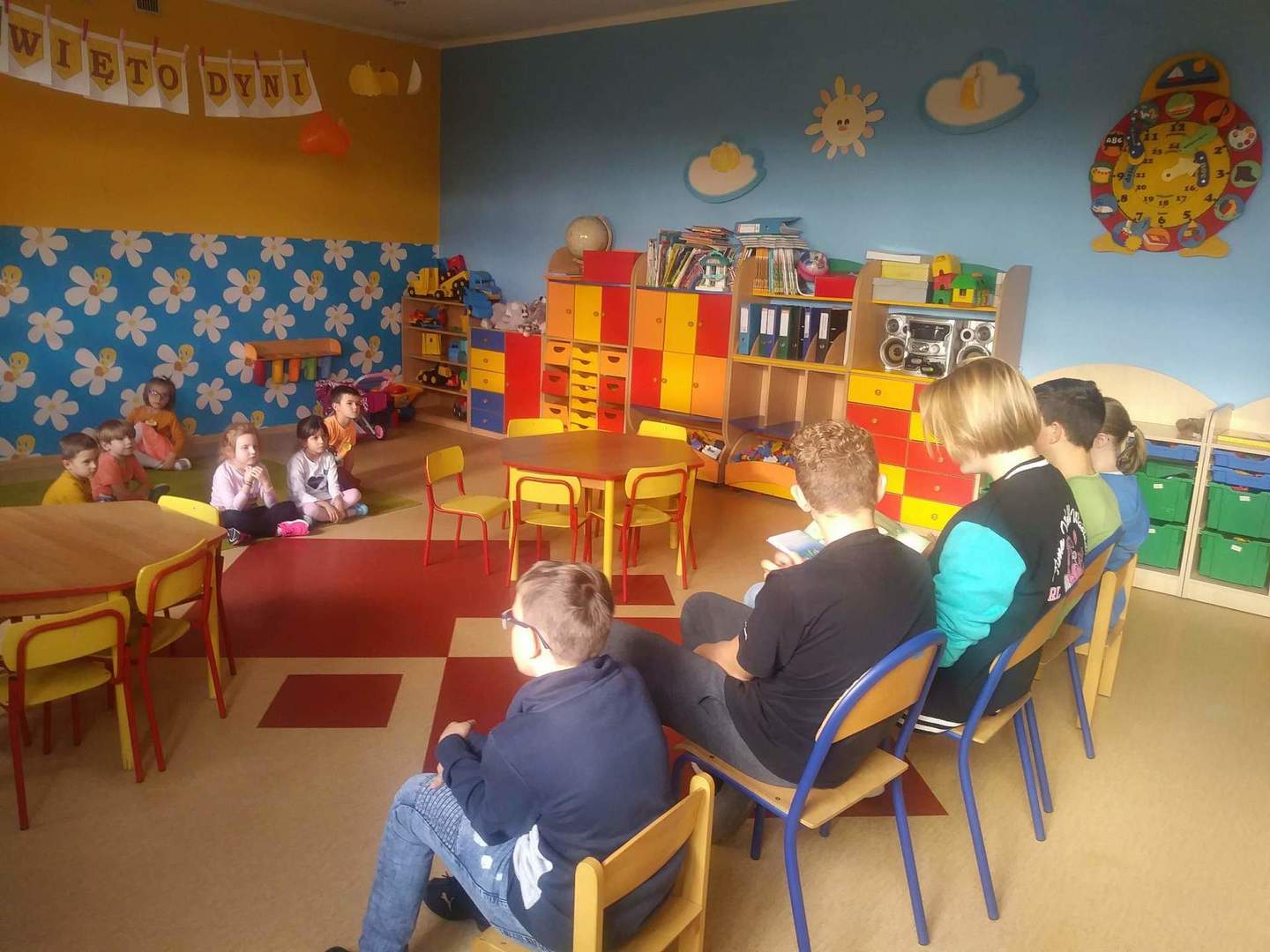 Zdjęcie przedstawia przedszkolaków oraz uczniów klasy VIII podczas czytania bajeczki.