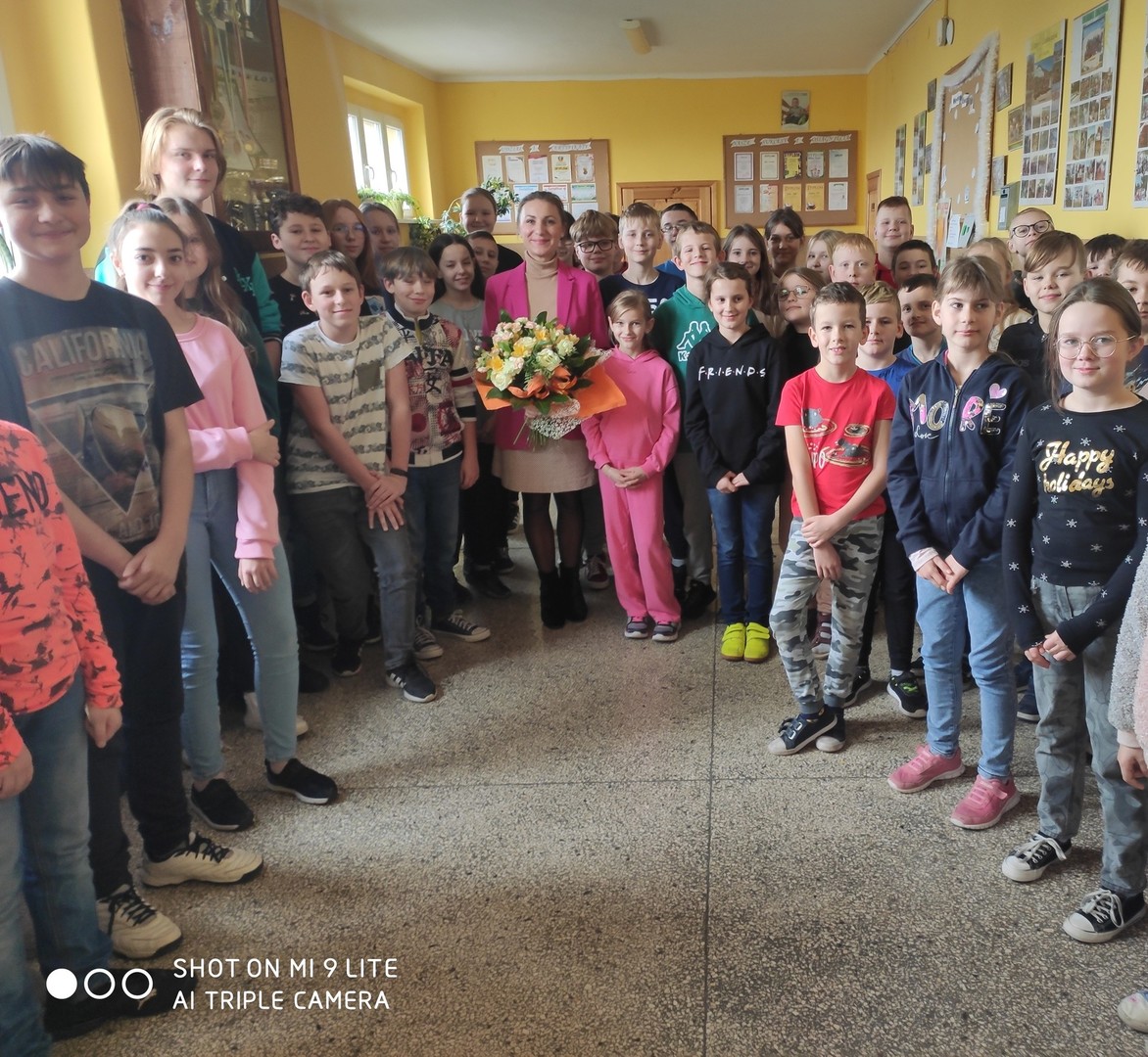 Pani Milena Zogłowek z uczniami naszej szkoły na szkolnym korytarzu.