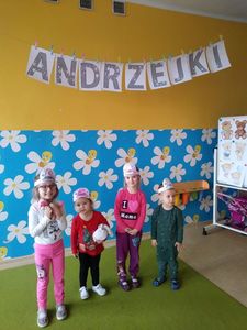 Zdjęcie przedstawia uśmiechniętych przedszkolaków, w tle napis „Andrzejki”, sala przedszkola.