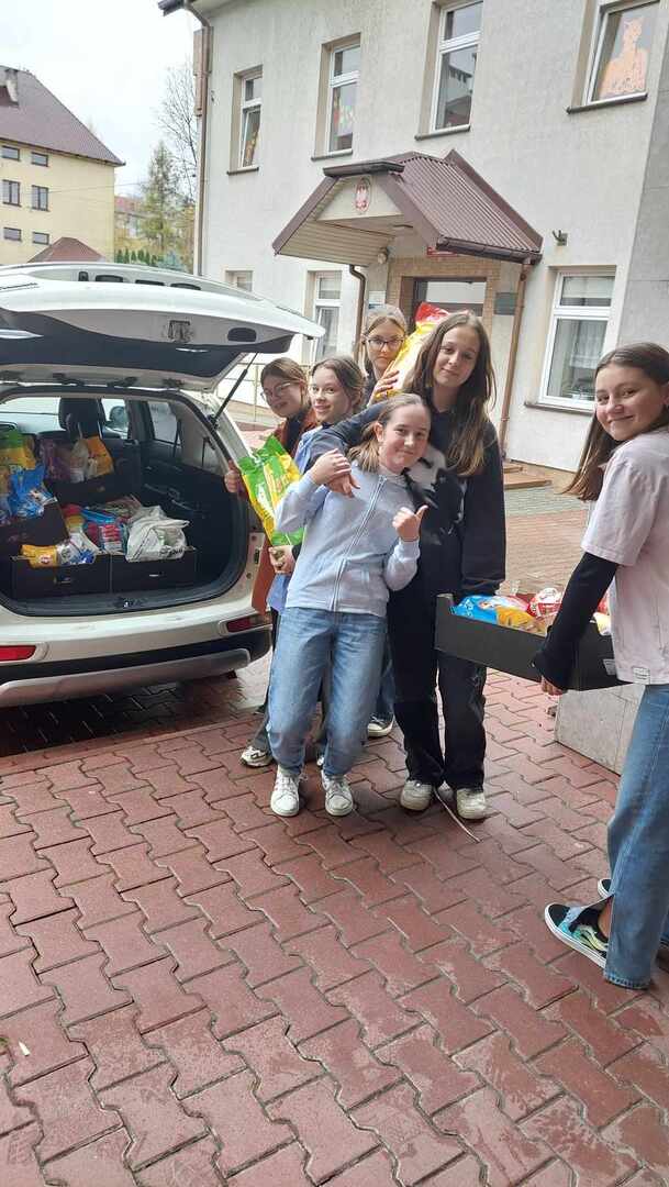 Uczniowie 7b przenoszą karmę ze szkoły do samochodu
