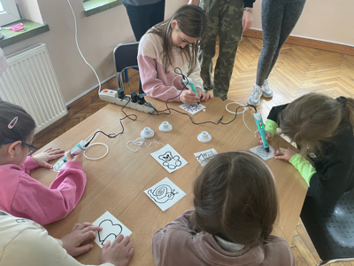 Dzieci przy stoliku rysują długopisami 3D