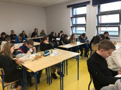 uczniowie przy stolikach rozwiązują zadania konkursowe