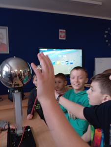 Chłopcy obserwują przenoszenie się ładunku elektrycznego w generatorze Van de Graaffa