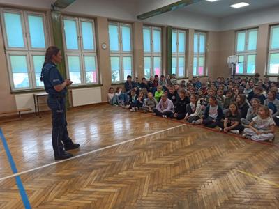 uczniowie zgromadzeni w auli słuchają prelekcji policjantki