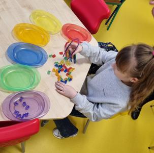 Dziewczynka segreguje elementy. Ćwiczenia motoryki małej.