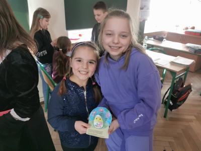 Dwie dziewczynki pokazują wspólnie wykonaną pracę plastyczną.