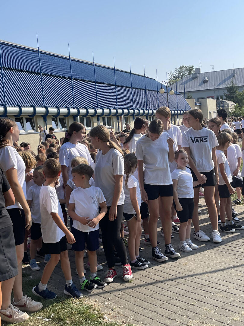Grupa uczniów w strojach sportowych oczekuje na start biegu