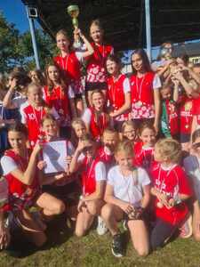 Grupa dziewcząt w strojach sportowych reprezentujących szkołę w biegach