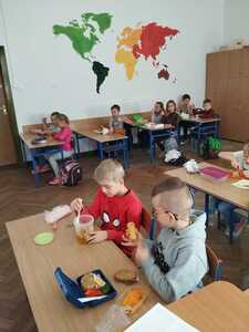 Uczniowie jedzą zdrowe śniadanie siedząc w ławce