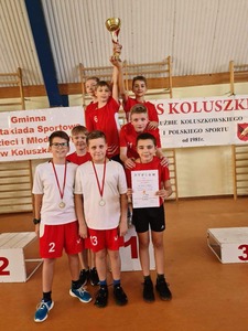 chłopcy w strojach sportowych trzymają puchar