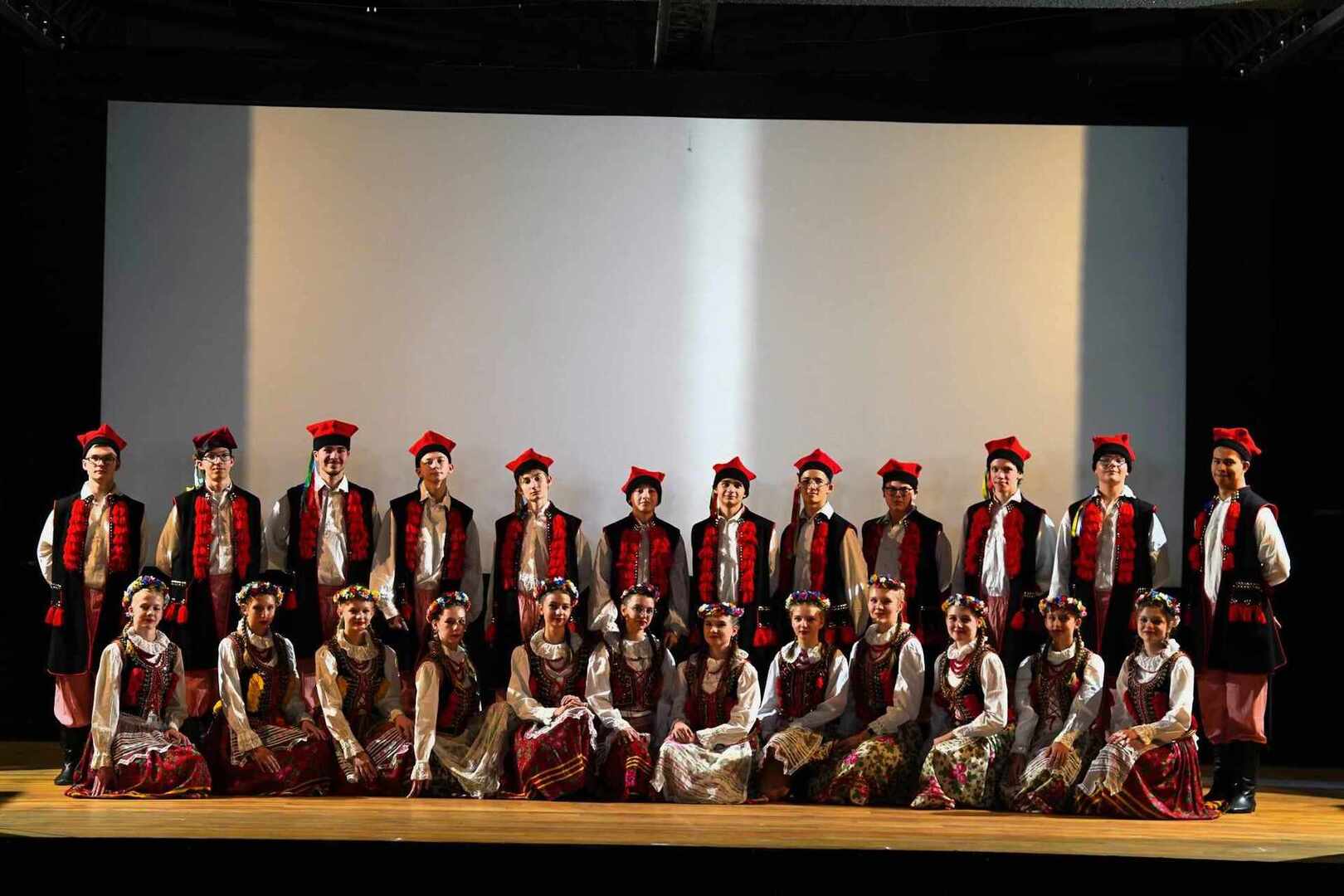 Zdjęcie grupowe tancerzy na scenie w strojach ludowych