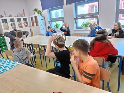 Uczniowie w sali lekcyjnej z pracują w goglach VR 