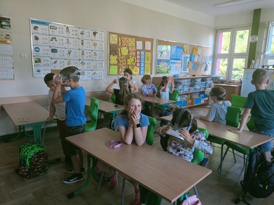 Grupa młodszych uczniów w sali lekcyjnej, maja na sobie gogle VR