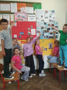 Uczniowie przy tablicy korkowej prezentują plakaty o Europie i miastach europejskich.