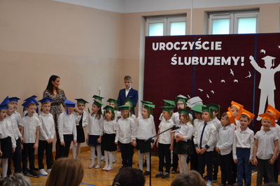 uczniowie klas pierwszych w kolorowych biretach