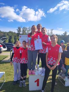 Uczennice stoją na podium z dyplomem za zajęcie l miejsca  w Powiatowych Biegach Sztafetowych.
