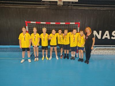 Uczniowie stoją z otrzymanymi medalami za udział w regionalnym turnieju piłki ręcznej.