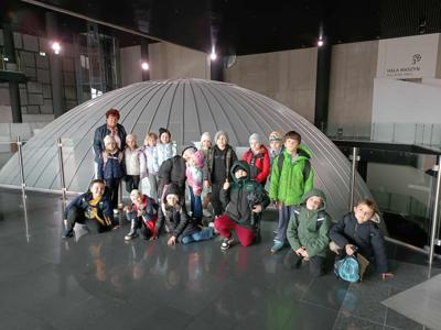 Dzieci stoją przed kopułą planetarium.