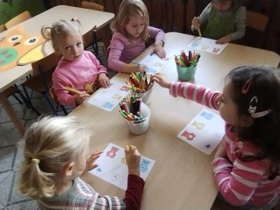 Dzieci przy stoliku kolorują bajkowy obrazek
