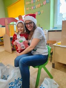 Nauczycielka i dziewczynka pozują do zdjęcia w mikołajowym stroju z upominkiem