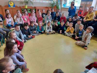 Przyszli uczniowie w szkolnej sali siedzą na podłodze