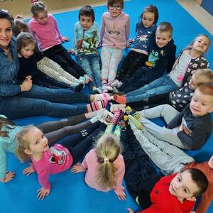 Dzieci z nauczycielką pozują w kole w kolorowych skarpetkach