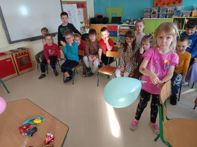 Dziewczynka wykonuje eksperyment z balonem zaczepionym do poziomej linki.