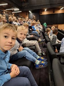 Dzieci siedzą na widowni w teatrze.