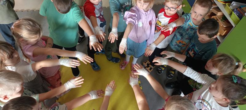 Dzieci pokazują zabandażowane przez pielęgniarkę ręce.
