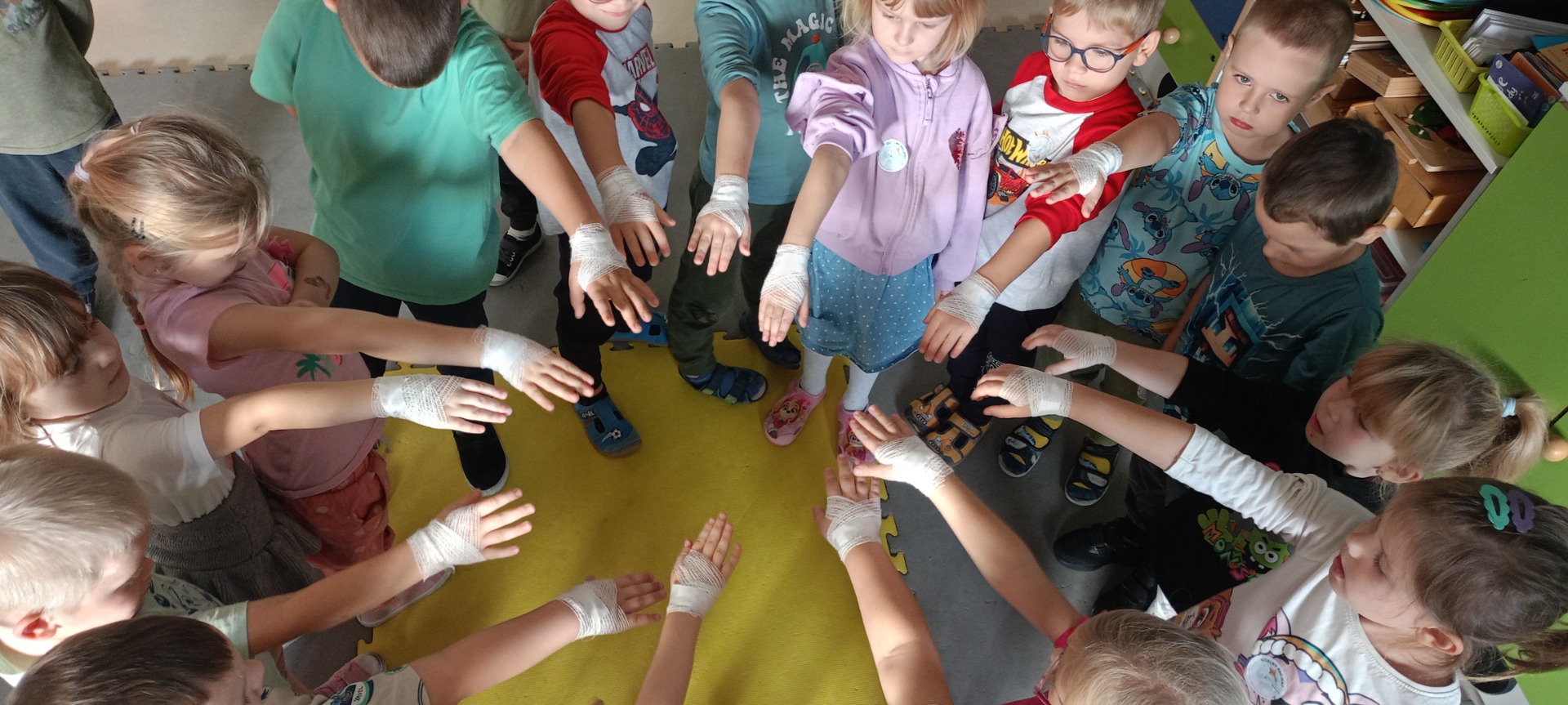 Dzieci pokazują zabandażowane przez pielęgniarkę ręce.