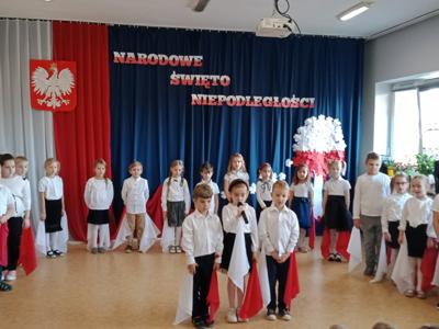 Troje dzieci ubranych na galowo występuje przed przedszkolakami