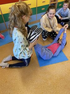 Dwie dziewczynki udzielają pomocy koleżance przy omdleniu