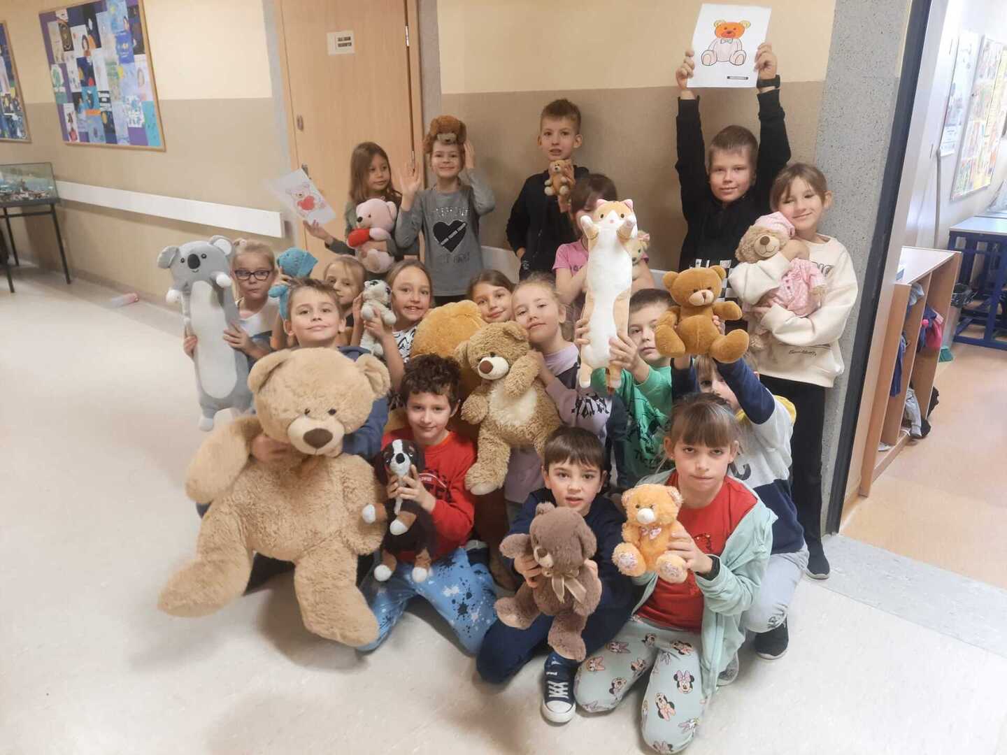 Dzieci z pluszakami na szkolnym korytarzu