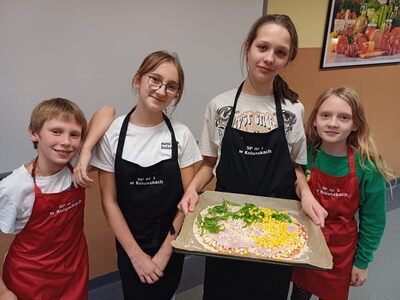 Dziewczynki i chłopiec prezentują wykonaną pizzę
