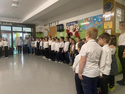 Uczniowie ubrani na galowo śpiewający hymn.