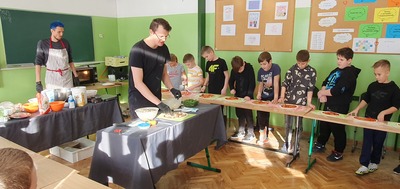 Pan Łukasz tłumaczy klasie trzeciej w jaki sposób wykonać pizzę.