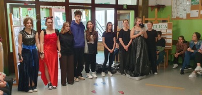 Modelki w strojach wieczorowych wraz z projektantami.