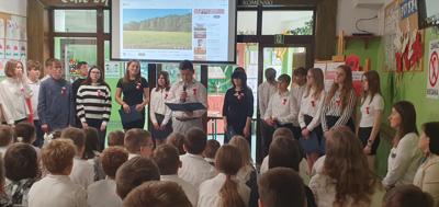 Uczniowie ubrani na galowo z biało-czerwonymi kotylionami biorą udział w przedstawieniu z okazji Narodowego Święta Niepodległości.