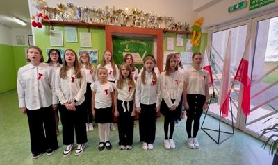 Chór szkolny - grupa dziewcząt ubrana na galowo śpiewa pieśń "My Pierwsza Brygada".