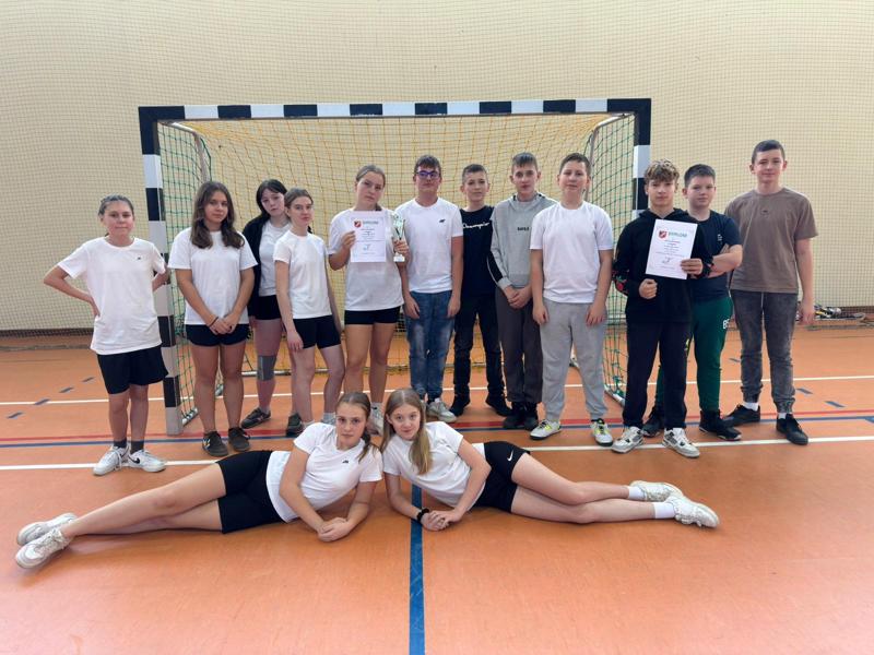Zdjęcie grupowe dziewcząt i chłopców biorących udział w zawodach gminnych Igrzysk Młodzieży Szkolnej w piłce ręcznej.