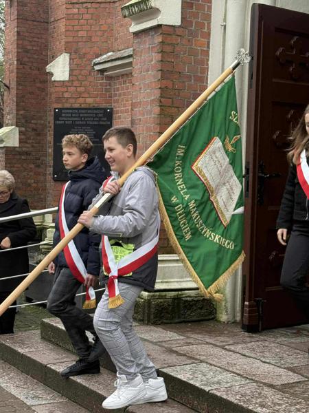 Dwójka chłopców z klasy VII wychodzi z kościoła niosąc sztandar.