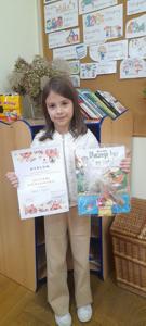 Helenka prezentuje dyplom i nagrodę książkową.